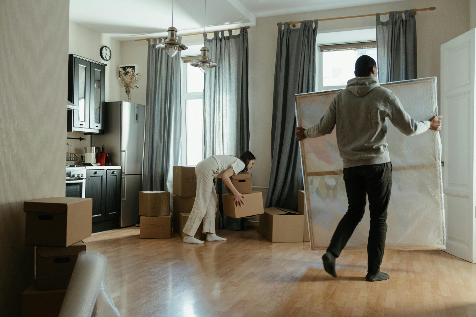 A young couple unpacks boxes in their new apartment, arranging their belongings.