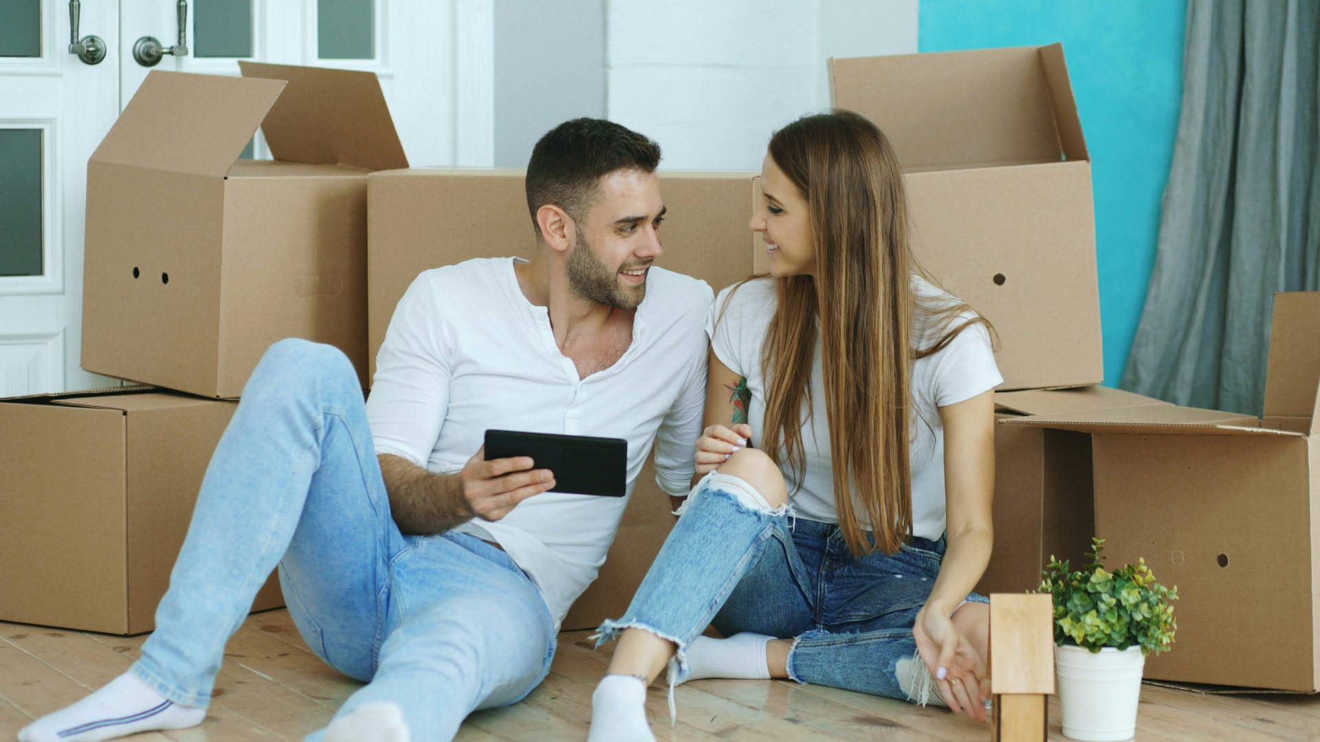 Couple looking at tablet surrounded by moving boxes